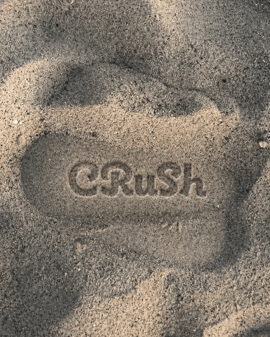 七里ヶ浜の砂に描かれた CRUSH のロゴ